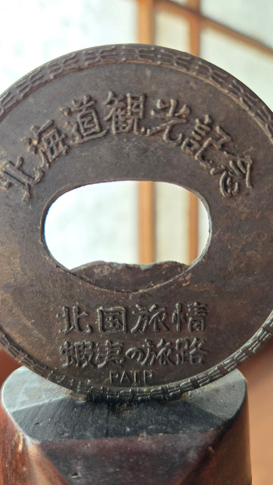 Décapsuleur souvenir Hokkaido vintage — Médaillon en métal gravé & socle bois sculpté style Aïnou