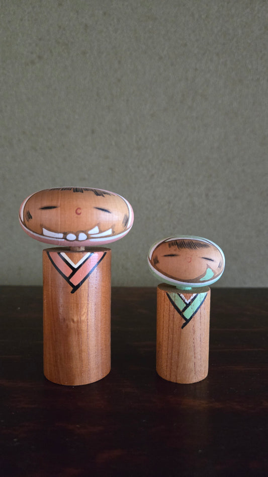 Paire de kokeshi créatives 🌸 — têtes ovales aplaties, chevrons géométriques rose & vert menthe