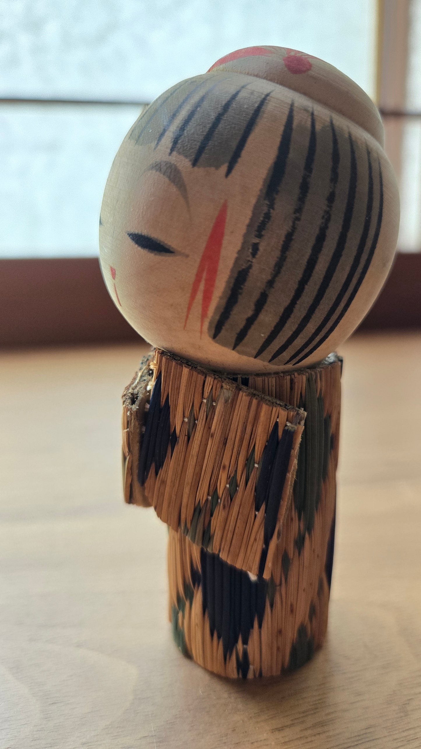 🪆 Kokeshi japonaise — Vêtement de paille tressée (mino), chevelure striée, visage aux yeux mi-clos — Vintage