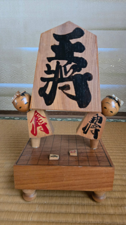 ♟️ Objet décoratif « pièce de shōgi géante » porté par deux kokeshi