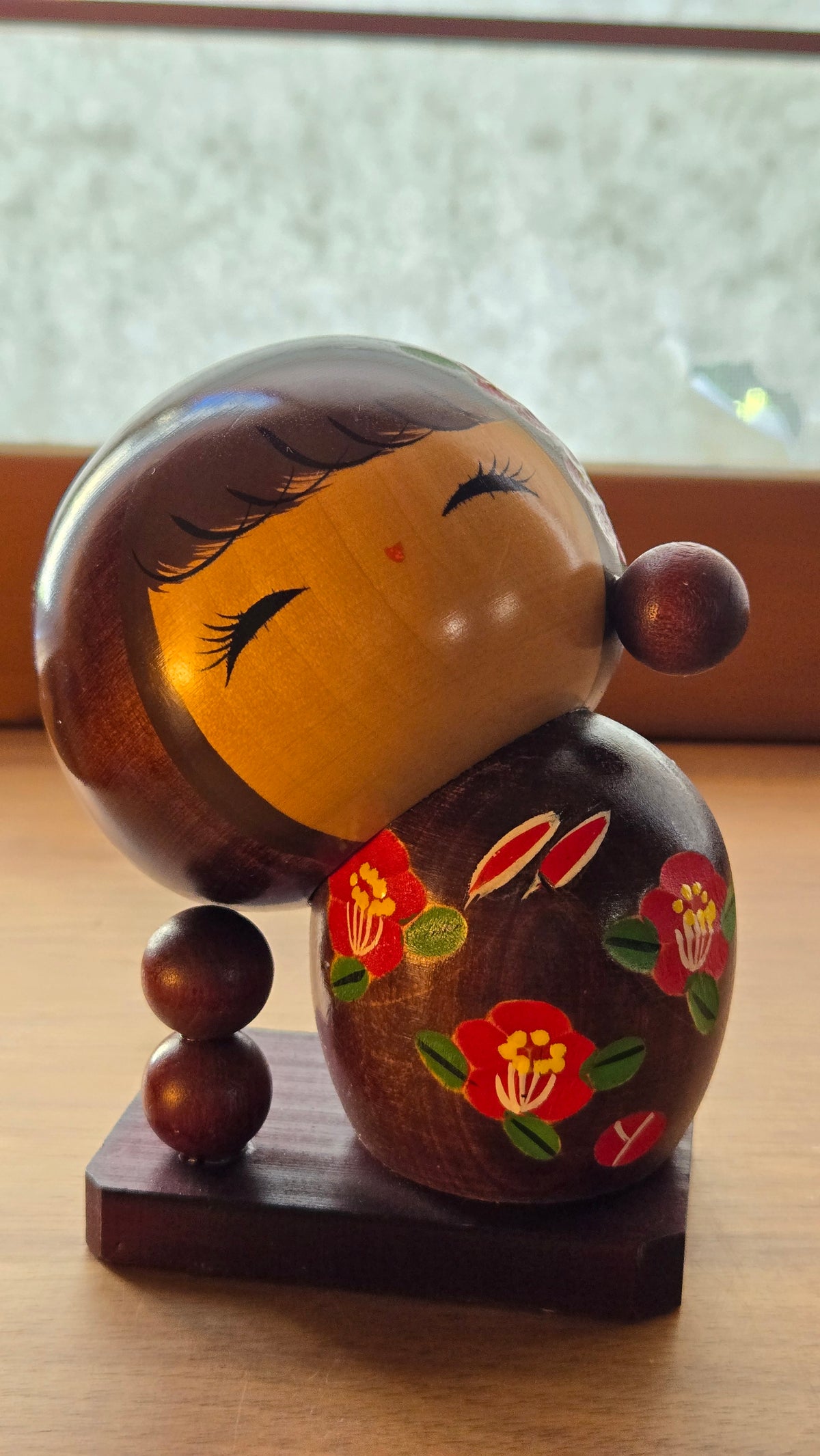 🎎 Kokeshi sōsaku inclinée sur socle – camélias rouges, bois brun