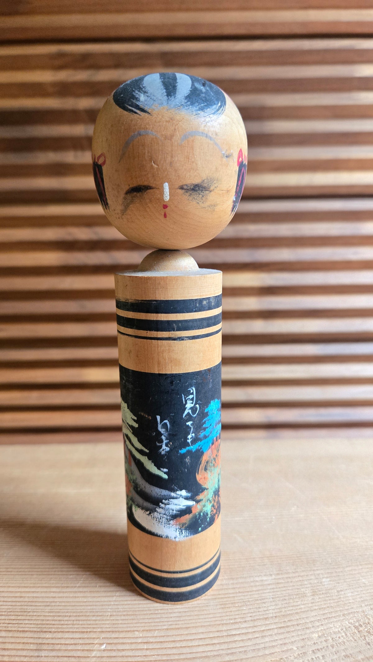 🎎 Kokeshi sōsaku à scène de paysage peinte sur fond noir, pin bleu et soleil orange