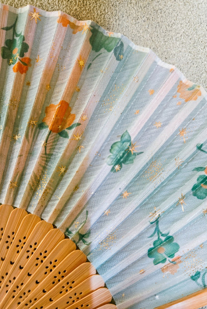Éventail pliant japonais en tissu – fleurs vertes et orangées, étoiles dorées, lames ajourées